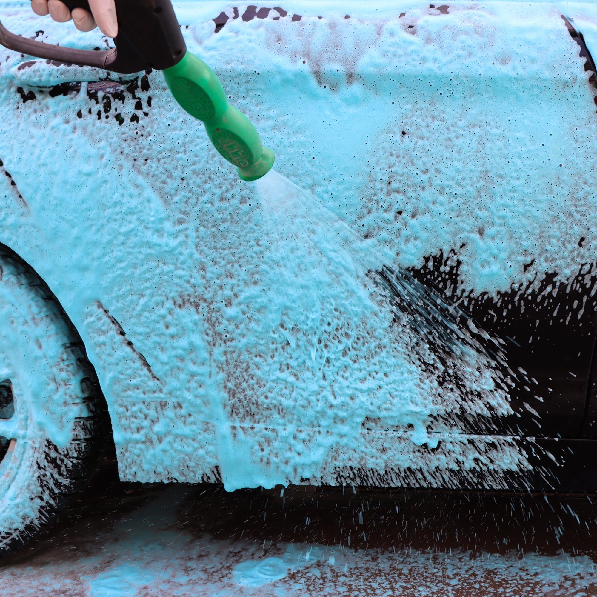 Blue coloured snow foam being applied to a car panel with a foam lance