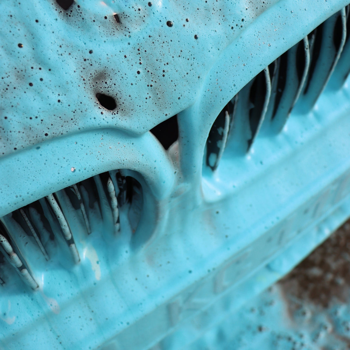 Blue coloured foam clinging to a front grille, close up